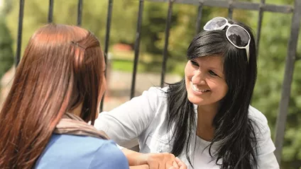 woman talking to teenage girl outdoors