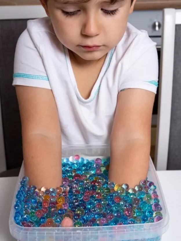 Autistic boy playing with water beads